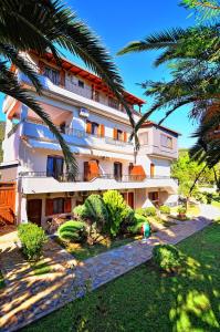 un grand bâtiment avec des palmiers devant lui dans l'établissement Villa Ilias, à Parga