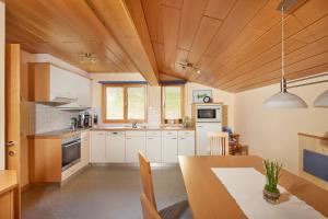 a kitchen with white cabinets and a wooden ceiling at Schuler's Panoramablick in Silbertal