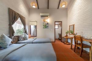 a bedroom with two beds and a table and a desk at An Nhien Retreat Phu Quoc with Yoga Daily & Beach access in Phu Quoc