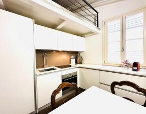 cocina con armarios blancos, mesa y sillas en ComeCasa Entire House Port View - Two Bedrooms en Saint-Tropez