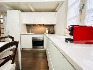uma cozinha com armários brancos e um aparelho vermelho no balcão em ComeCasa Entire House Port View - Two Bedrooms em Saint-Tropez