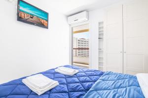 niebieskie łóżko w białym pokoju z oknem w obiekcie Acuarium II 5-B Apartment Levante Beach w mieście Benidorm +20 zdjęć