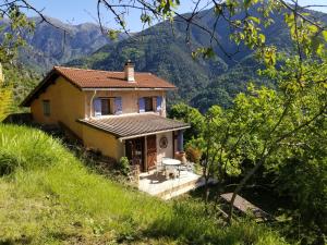 una pequeña casa en una colina con montañas en el fondo en Haut de grange en pierre, en Roquebillière