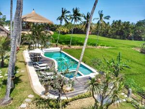 uma imagem de uma piscina num quintal com palmeiras em Coco Verde Bali Resort em Tanah Lot