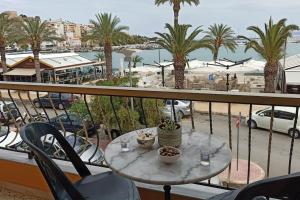 a table on a balcony with a view of a harbor at SeaShell apartment Sea View, Castle View 200metres from the Beach in Sitia