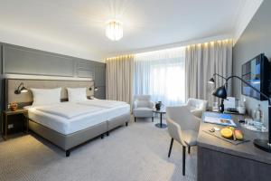 バート・クロイツナハにあるParkhotel Kurhausのベッド、デスク、テレビが備わるホテルルームです。