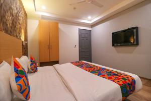 a hotel room with a bed and a flat screen tv at FabExpress La Serene - Near Yamuna Sports Complex in New Delhi