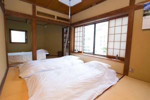 two beds in a room with two windows at Diplomat House very close to JR Station in Tokyo