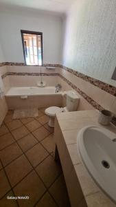 a bathroom with a sink and a toilet and a tub at Kruger Park Lodge Unit No. 243 in Hazyview