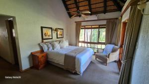a bedroom with a bed and a chair and a window at Kruger Park Lodge Unit No. 243 in Hazyview
