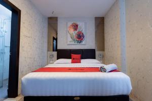 een slaapkamer met een groot wit bed met een rood kussen bij RedDoorz Premium near Grand Batam Mall in Nagoya
