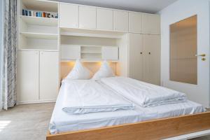 Schlafzimmer mit einem weißen Bett und weißen Schränken in der Unterkunft Neptun in Westerland