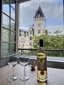 uma garrafa de vinho e dois copos numa mesa com um castelo em Vue magique sur le château dans un quartier populaire em Pau