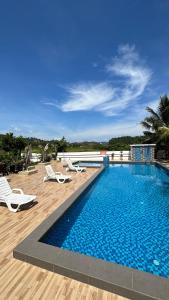 uma piscina com duas espreguiçadeiras e uma piscina em Cenang Room Rahsia Motel em Pantai Cenang