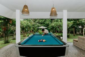 a man playing pool on a pool table at Agung Wiwin Homestay & Restaurant in Mengwi