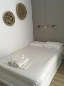 a bed with white sheets and a towel on it at Cristi Rooms in Livadi