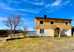 a yellow and white house on top of a hill at Sunyard House Lofoten in Leknes