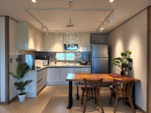 a kitchen with a wooden table and chairs in it at Daejeong Prabang in Seogwipo