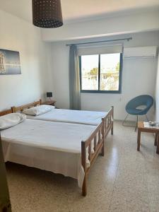 a bedroom with a bed and a chair and a window at Angela Holiday Apartments in Paphos City