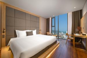 a bedroom with a large white bed and a large window at Estrella Boutique Hotel in Da Nang