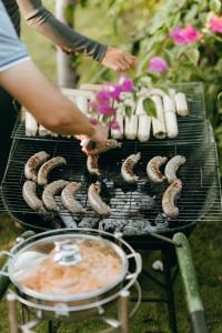 a person is cooking sausages on a grill at Palme villa - Venuestay 