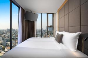 a bedroom with a large white bed and large windows at Estrella Boutique Hotel in Da Nang