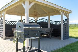 a gazebo with a grill and a picnic table at Kolory Lata - 365PAM KLIMATYZACJA I PLAC ZABAW W OBIEKCIE in Sarbinowo