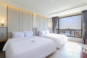 a hotel room with two beds and a large window at H avenue Kijang Ilgwang in Busan