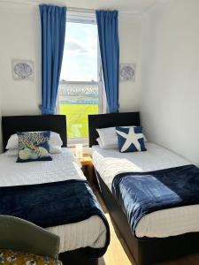 een slaapkamer met 2 bedden, blauwe gordijnen en een raam bij Keepers Rest Scarborough North Bay in Scarborough
