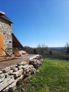 eine Holzterrasse mit einer Bank und einer Steinmauer in der Unterkunft Les Hauts de Bagadou in Martel