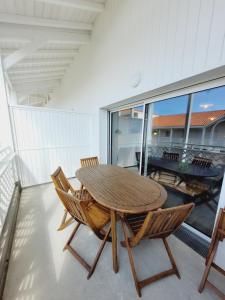 a wooden table and chairs on a balcony at Escapade Ensoleillée in Mimizan