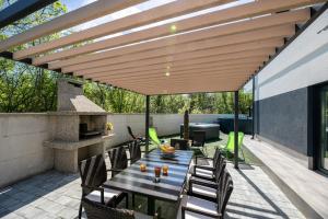 a patio with a table and chairs under a wooden pergola at Villa Veroniq in Županje