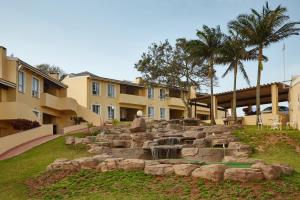 a fountain in a yard in front of a building at First Group Chaka's Rock Chalets in Ballito