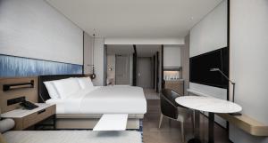 Cette chambre comprend un lit, un bureau et une télévision. dans l'établissement Guangzhou Marriott Hotel Nansha, à Canton