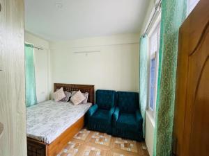 ein kleines Zimmer mit einem Bett und einem blauen Sofa in der Unterkunft HILLS HOME in Shimla