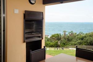 a view of the ocean from a patio with a oven at First Group Chaka's Rock Chalets in Ballito
