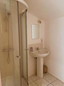 een badkamer met een wastafel en een glazen douche bij Charming village house with pool in Autignac