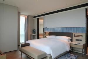 Guangzhou Marriott Hotel Nansha في قوانغتشو: غرفة نوم بسرير ابيض كبير وكرسي
