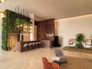 a lobby with chairs and a bar with plants at Leonardo Boutique Hotel Larnaca in Larnaca