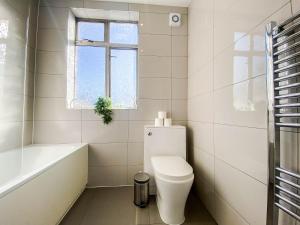 a white bathroom with a toilet and a bath tub at Urban Oasis l 3-Bed Gem in Watford Town Center in Watford