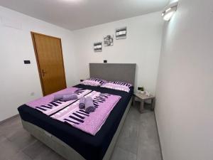 a bedroom with a bed with purple blankets and pillows at Apartman Pako i Ivano in Novi Vinodolski