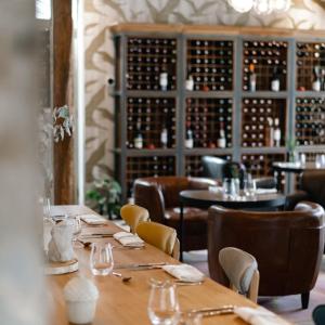 uma sala de jantar com mesas e cadeiras e garrafas de vinho em Mercure Parc du Coudray - Barbizon em Le Coudray-Montceaux