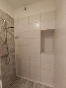 W łazience znajduje się prysznic z białymi kafelkami. w obiekcie Gościniec Mazurek , Apartament przy Jeziorze Niegocin w mieście Wilkasy