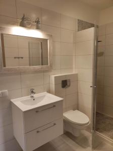 ein Badezimmer mit einem Waschbecken, einem WC und einem Spiegel in der Unterkunft Gościniec Mazurek , Apartament przy Jeziorze Niegocin in Wilkasy
