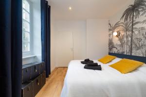 1 dormitorio con 1 cama grande con almohadas amarillas en Superbe appartement avec jardin Dinan centre - Jerzual, en Dinan