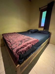 a bed with a red blanket on it in a room at Big Daddy´s Surfcamp in Pasanggaran