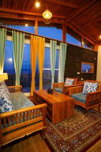 a living room with wooden furniture and a large window at Shivoham Himalayan Resort in Almora