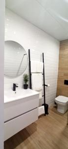 uma casa de banho com um lavatório, um espelho e um WC. em Limerencia: tu hogar en este blanco pueblo em Frigiliana