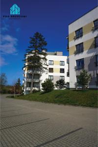 a white building with a tree in front of it at Pod Brzozami Apartamenty Rezydencja Ustronie Morskie in Ustronie Morskie
