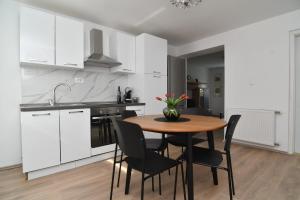a kitchen with white cabinets and a wooden table and chairs at Apartman Gluić in Sinj